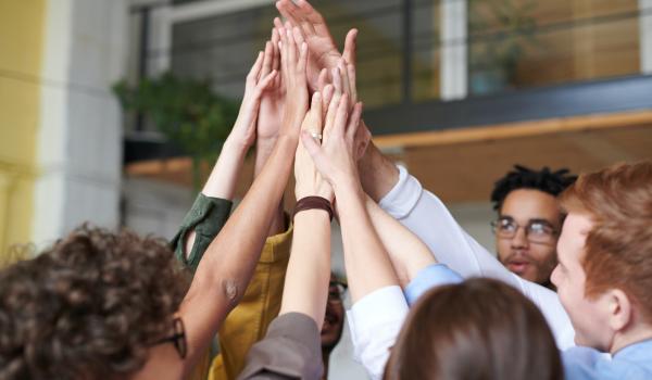 Ragazzi in cerchio con tutte le mani in alto al centro
